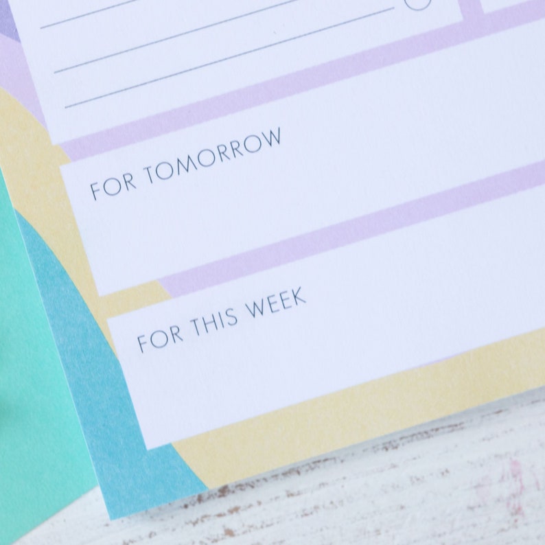 Op de afbeelding: Een witte plannerpagina met een lichtpaarse en gele achtergrond. De pagina heeft twee secties met de labels "Voor morgen" en "Voor deze week".