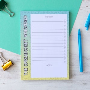 May include: A notepad with a gradient background of yellow, green, and blue. The notepad has a to-do list and notes section. The text "THE SPREADSHEET WHISPERER" is printed on the side of the notepad.