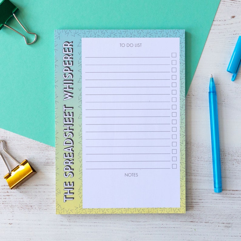 May include: A notepad with a gradient background of yellow, green, and blue. The notepad has a to-do list and notes section. The text "THE SPREADSHEET WHISPERER" is printed on the side of the notepad.