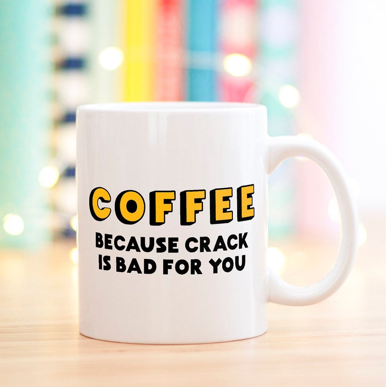 K&ouml;nnte beinhalten: Wei&szlig;e Keramik-Kaffeetasse mit schwarzem Text, der "COFFEE because crack is bad for you" lautet. Der Text "COFFEE" ist gelb und schwarz umrandet.
