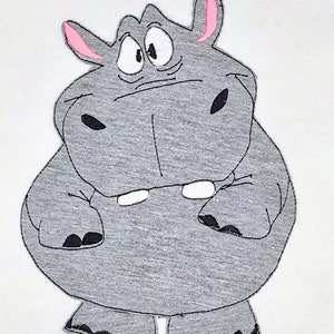 Könnte beinhalten: Ein graues Cartoon-Nilpferd mit rosa Ohren und großen Augen. Das Nilpferd steht auf weißem Hintergrund.