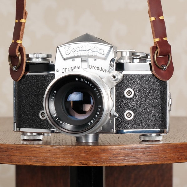 One brown or dark brown leather camera strap for vintage cameras.