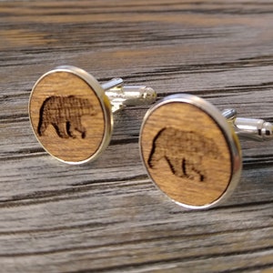 May include: A pair of wooden cufflinks with a silver finish. Each cufflink features a laser-engraved bear silhouette.