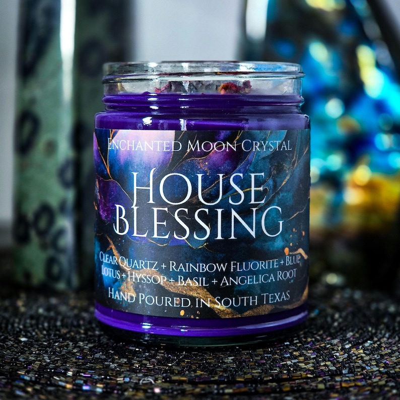 Pu&ograve; includere: Una candela in barattolo di vetro con riempimento di cera viola e un'etichetta che recita "ENCHANTED MOON CRYSTAL HOUSE BLESSING". L'etichetta presenta un design blu scuro e viola con gli ingredienti: Quarzo chiaro, Fluorite arcobaleno, Loto blu, Issopo, Basilico e Radice di angelica.