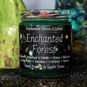 Może przedstawiać: Zielony szklany słoik z czarną etykietą z napisem "Enchanted Forest" w białym skrypcie. Etykieta zawiera składniki takie jak ametyst i lawenda. Widoczny jest r&oacute;wnież tekst "Hand Poured in South Texas".