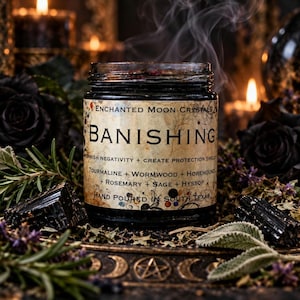 Top-down photograph of Enchanted Moon Crystal Season of the Witch intention candle displaying black wax adorned with smoky quartz, polished obsidian stones, colorful dried rose petals, and herbal botanicals. Styled on a decorative antique gold moon and star tray with deep red roses, purple lavender, illuminated crystal points, and glowing candles. Dark romantic witchcraft-inspired photography highlighting the candle's crystal toppings, botanical details, and earthy autumn ritual aesthetic.