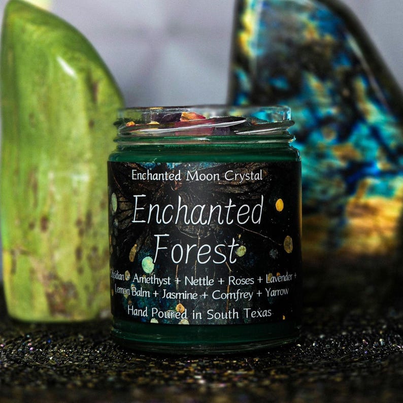 Może przedstawiać: Zielony szklany słoik z czarną etykietą z napisem "Enchanted Forest". Etykieta zawiera składniki takie jak ametyst, pokrzywa i lawenda. Słoik jest wypełniony zieloną substancją i zwieńczony kolorowymi kawałkami. Widoczny jest r&oacute;wnież tekst "Hand Poured in South Texas".