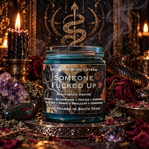 Hand-poured Someone Fucked Up candle displayed against an ornate golden serpent symbol, surrounded by burning black taper candles, scattered rose petals, and amethyst crystals. The turquoise glass jar features a bold gothic label identifying this black magic hexing candle. Rich amber lighting, dark floral decorations, and drifting incense smoke create an atmospheric witchcraft ritual setting.