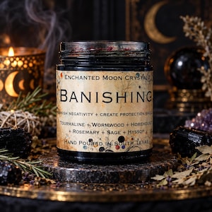 Dark mystical photograph of Enchanted Moon Crystal Banishing candle, hand poured in a black glass jar with an antique botanical label. Displayed on a stone pedestal surrounded by black tourmaline crystals, dried rosemary, sage, sacred herbs and glowing candlelight. A golden crescent moon and curling incense smoke create an enchanting occult atmosphere. Witchcraft inspired protection candle for banishing negativity, energetic cleansing, spiritual shielding, ritual work and gothic altar decor