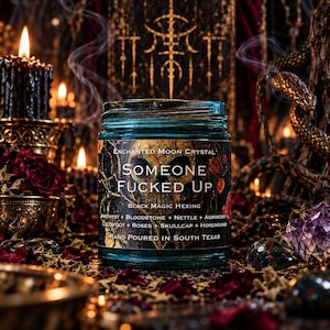 Someone Fucked Up intention candle in a turquoise glass jar displayed on a dark gothic altar featuring antique golden serpent decorations, glowing black taper candles, purple amethyst clusters, and deep crimson roses. Wisps of incense smoke drift through the warm amber lighting, creating a mysterious atmosphere for this handcrafted black magic hexing and banishment candle.