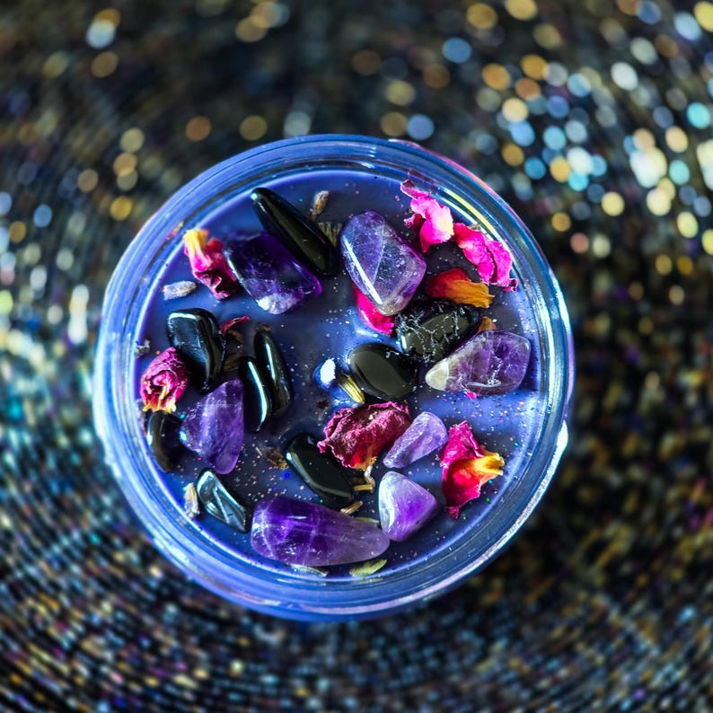 Detailed top view of purple Witching Hour candle decorated with black tourmaline stones, dried roses, lavender and rosemary