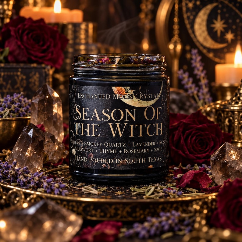 Direct front view of Season of the Witch handmade intention candle by Enchanted Moon Crystal, featuring a black glass jar with an original vintage gold moon label and dark wax topped with crystals and dried flowers. Displayed on an ornate antique gold pedestal surrounded by smoky quartz crystals, lavender, deep burgundy roses, and softly glowing candles. Luxurious gothic witchcraft-inspired product photography with rich amber lighting, celestial decor, and a mysterious magical atmosphere.
