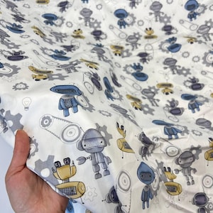 Peut inclure: Tissu blanc avec un motif répété de robots bleus, gris et jaunes. Les robots sont de tailles et de formes différentes, et ils sont entourés d'engrenages et d'autres éléments mécaniques.