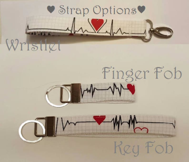 May include: Three white fabric keychains with a black EKG line and red heart designs. The keychains are labeled "Wristlet", "Finger Fob", and "Key Fob".