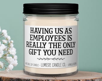 May include: A white soy candle in a clear glass jar with a black lid. The label reads "HAVING US AS EMPLOYEES IS REALLY THE ONLY GIFT YOU NEED".