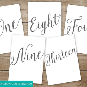 May include: Five white cards with gray calligraphy numbers on them. The numbers are "One", "Eight", "Four", "Nine", and "Thirteen".