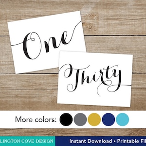 May include: Two printable table number cards with the numbers "One" and "Thirty" written in a cursive font. The cards are white with black text and are displayed on a wooden background. The image also includes a row of five color swatches: black, gray, gold, navy blue, and teal.