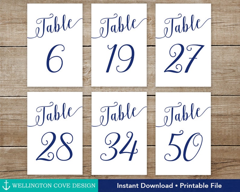 May include: Six white table number cards with navy blue script and numbers. The cards are arranged on a wooden surface. Numbers include 6, 19, 27, 28, 34, and 50. The text "Instant Download &bull; Printable File" is at the bottom.