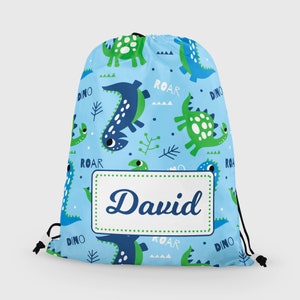 May include: A light blue drawstring bag with a dinosaur pattern. The bag has a white name tag with the name "David" printed in blue. The bag is decorated with green and blue dinosaurs, the words "Roar" and "Dino", and green leaves.