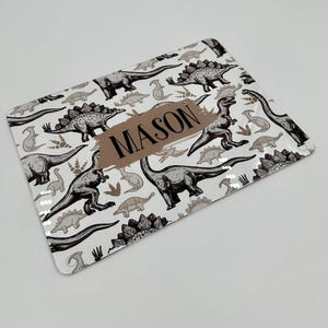 May include: Rectangular tray featuring a white background with a repeating pattern of grey and brown dinosaurs. The word "MASON" is printed in brown on a brown rectangular shape in the centre of the tray.