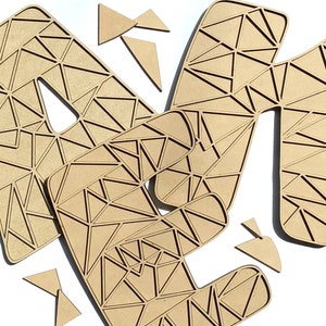 Puede incluir: Un conjunto de tres letras de madera, A, M y N, en un patr&oacute;n geom&eacute;trico. Las letras est&aacute;n hechas de madera marr&oacute;n claro y tienen un dise&ntilde;o triangular.