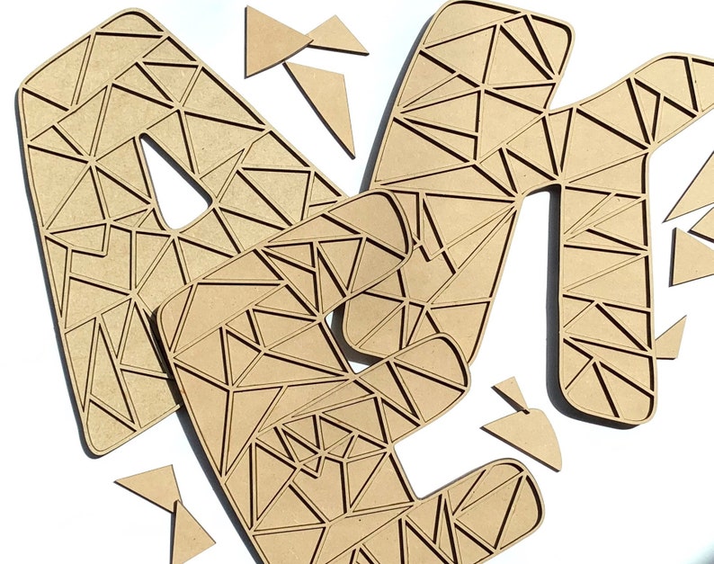 Puede incluir: Un conjunto de tres letras de madera, A, M y N, en un patr&oacute;n geom&eacute;trico. Las letras est&aacute;n hechas de madera marr&oacute;n claro y tienen un dise&ntilde;o triangular.