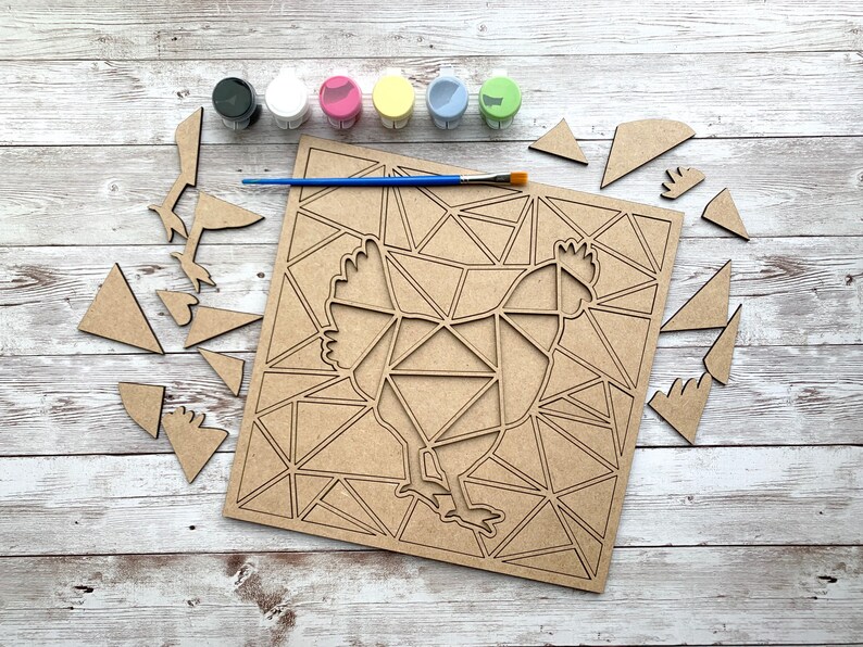 May include: A wooden craft kit featuring a geometric chicken design. The kit includes a wooden base, paint, and a brush. The pieces are ready to be painted and assembled.