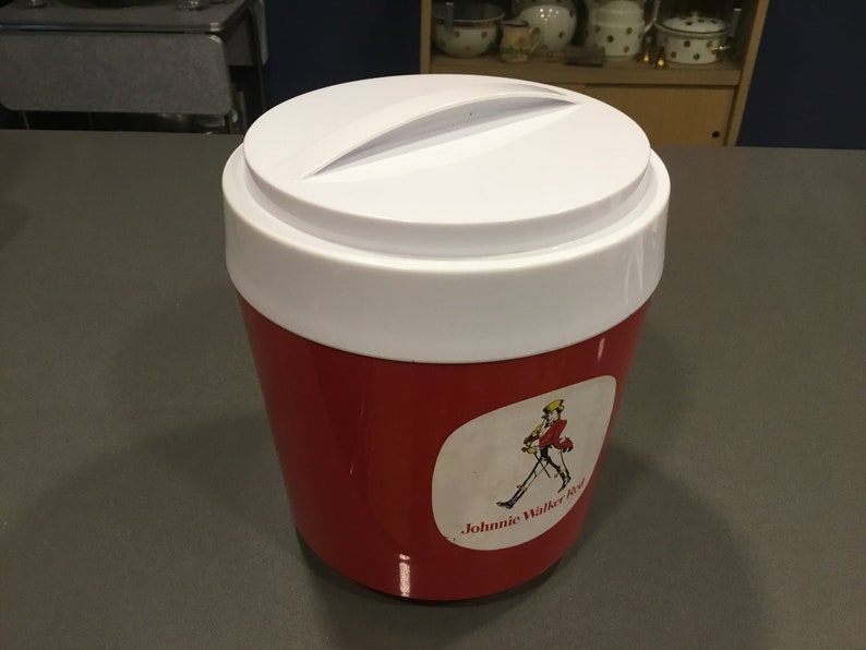 May include: Red and white insulated cooler with a white lid and a Johnnie Walker Red label featuring a man in a red jacket walking with a cane.