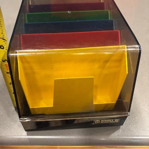 May include: A vintage Minidex 60 modular viewer with a clear plastic cover and a black base. The interior features colored dividers in yellow, red, blue, green, and purple. The unit is approximately 5 inches tall.