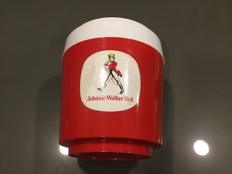 May include: Red and white plastic cooler with a Johnnie Walker Red label featuring a man in a red coat walking with a stick.