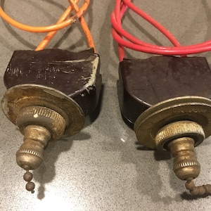 Może przedstawiać: Dwa vintage brązowe łańcuszki do ciągnięcia wentylatora sufitowego z mosiężnymi akcentami i pomarańczowymi i czerwonymi przewodami.