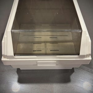 May include: A white plastic Memorex storage case with a clear, tinted lid. The case has a rectangular shape with a handle on the front. The Memorex logo is visible on the front of the case.