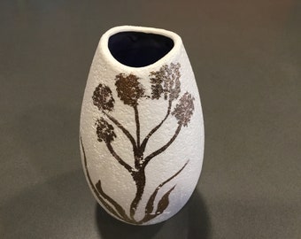 May include: White ceramic vase with a textured surface and a gold floral design. The vase has a blue interior.