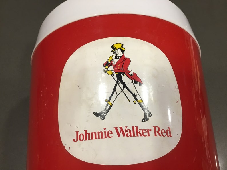 May include: Red and white cooler with a Johnnie Walker Red label featuring a man in a red jacket and black pants walking with a cane. The label also includes the text "Johnnie Walker Red".