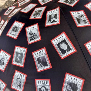 May include: Black umbrella featuring multiple TIME magazine covers with red borders. The covers display black and white images of various people. The umbrella is open, showcasing the design.