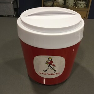 May include: A red and white cooler with a white lid and a Johnnie Walker Red label featuring a man in a red coat and a top hat walking with a cane.