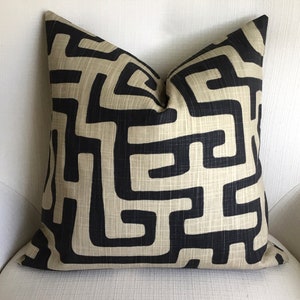 May include: A decorative throw pillow with a geometric pattern in black and beige. The pattern is a maze-like design with sharp angles and lines.