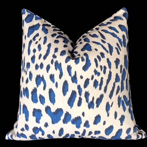 Puede incluir: Una almohada de tiro de estampado de leopardo blanco y azul. La almohada est&aacute; hecha de una tela suave y texturizada.