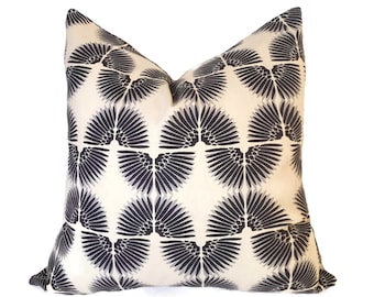 May include: A cream-colored throw pillow with a black and white geometric pattern of stylized wings.