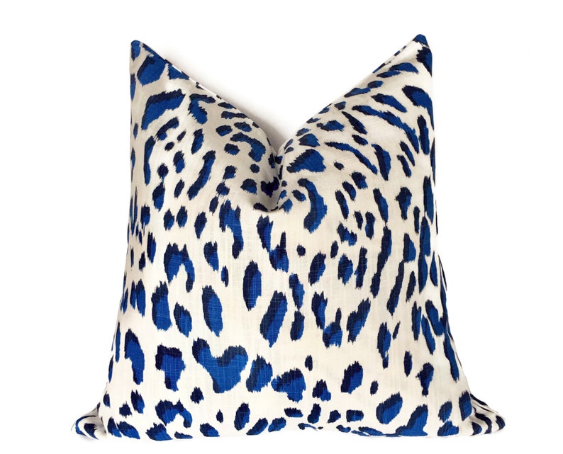 Puede incluir: Una almohada de tiro de estampado de leopardo azul y blanco. La almohada est&aacute; hecha de una tela suave y c&oacute;moda y tiene un brillo sutil.