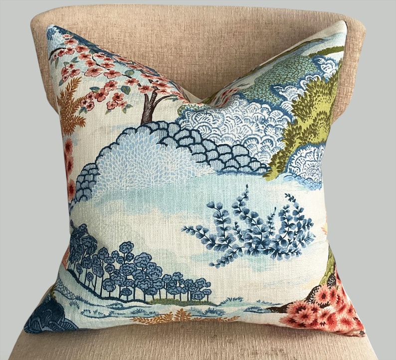 May include: A decorative pillow with a blue and green floral pattern on a white background. The pattern features trees, flowers, and leaves.