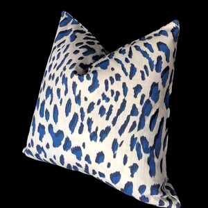 Puede incluir: Una almohada de tiro de estampado de leopardo blanco y azul. La almohada est&aacute; hecha de una tela suave y texturizada.