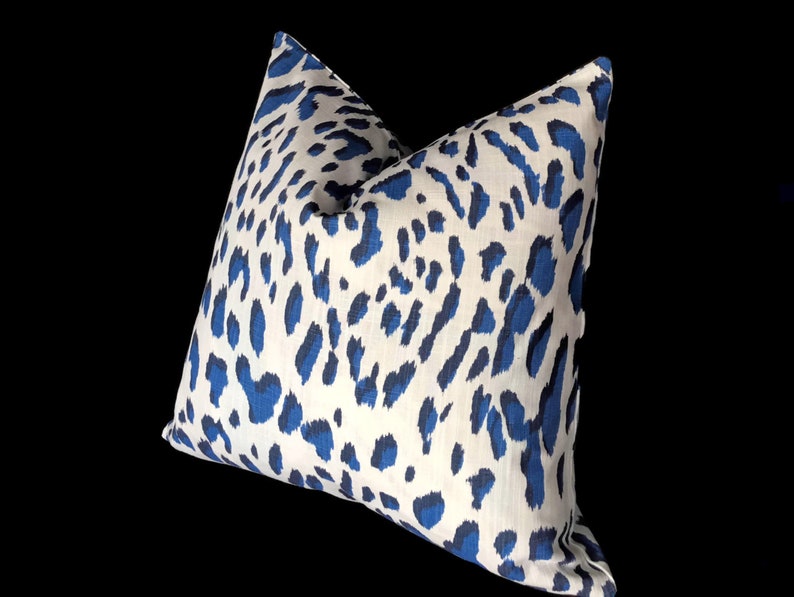 Puede incluir: Una almohada de tiro de estampado de leopardo blanco y azul. La almohada est&aacute; hecha de una tela suave y texturizada.