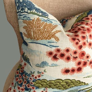 May include: A decorative throw pillow with a floral pattern featuring pink, blue, and green flowers on a white background. The pillow has a light blue and brown fern pattern in the upper left corner.