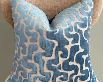 May include: A square throw pillow featuring a raised, velvet-like texture with an intricate, winding pattern in shades of light and medium blue against a neutral beige background. The design consists of continuous, organic, maze-like shapes.