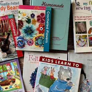 May include: A collection of craft books with colourful covers featuring various projects, including crocheted flowers, needle-felted teddy bears, patchwork style, and sewing machine projects.