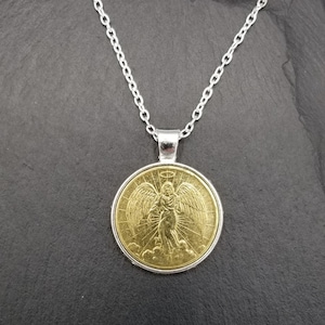 May include: A gold pendant necklace with a silver chain. The pendant features a detailed image of an angel with wings.