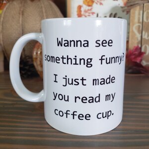May include: White ceramic coffee mug with black text that reads "Wanna see something funny? I just made you read my coffee cup."