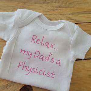 May include: White baby onesie with pink text that reads "Relax... my Dad's a Physicist".