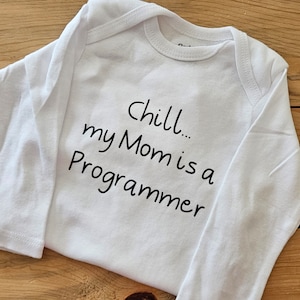 May include: White long-sleeved baby onesie with black text that reads "Chill... my Mom is a Programmer".